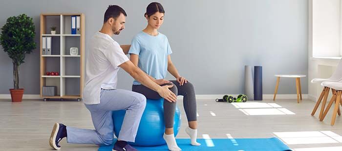 femme faisant un exercice d'ostéopathie sur un ballon accompagné d'un ostéopathe