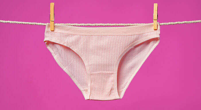 culotte rose accrochée àune corde à linge à l'aide de deux pinces à linge