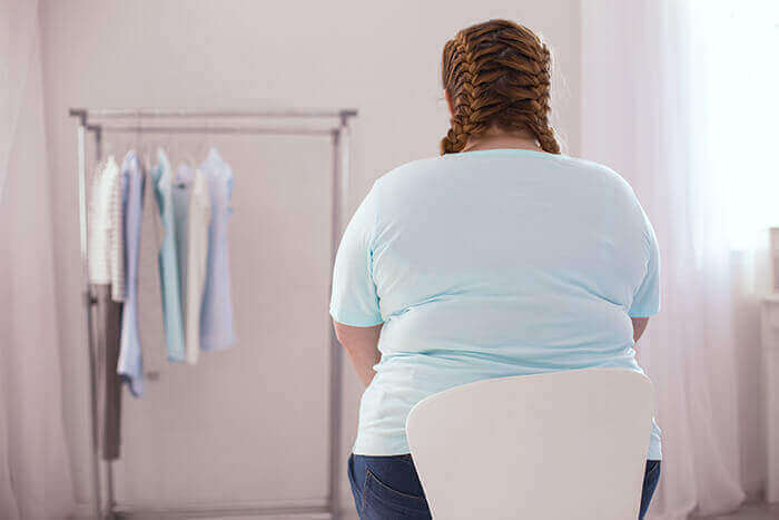 Mujer obesa de dos asistentes en una chaise face con un portante de ropa.