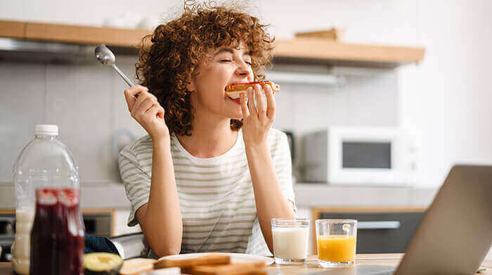 femme croquant à pleines dents dans une tartine au cours de son petit-déjeuner
