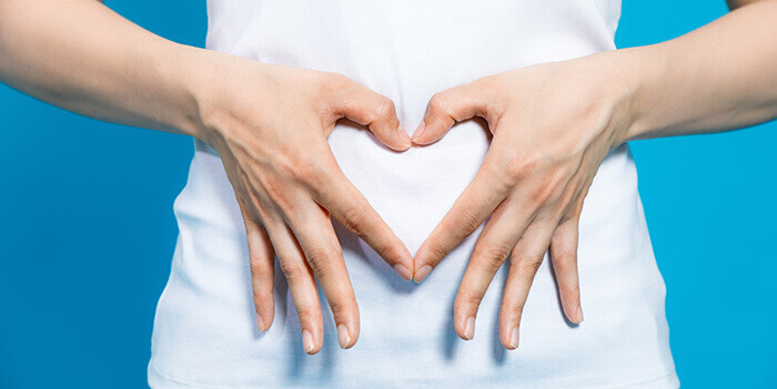 plan sur les mains d'une femme en coeur devant son ventre