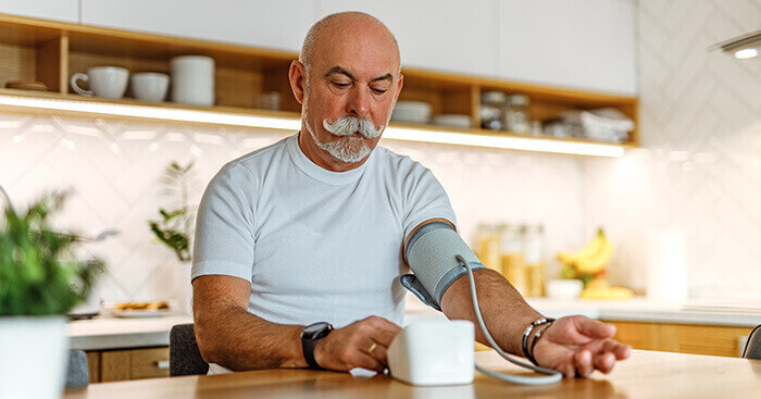 Homme prenant sa tension assis dans sa cuisine