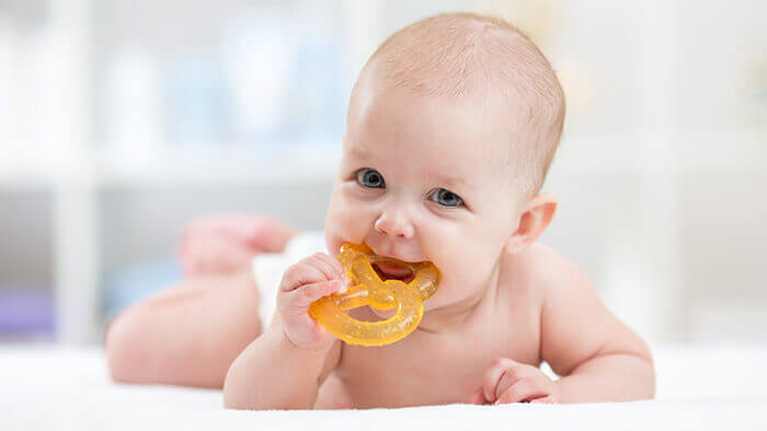 bébé machouillant un anneau de dentition