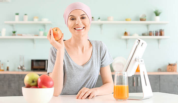 Femme atteinte d'un cancer tenant une pomme en main