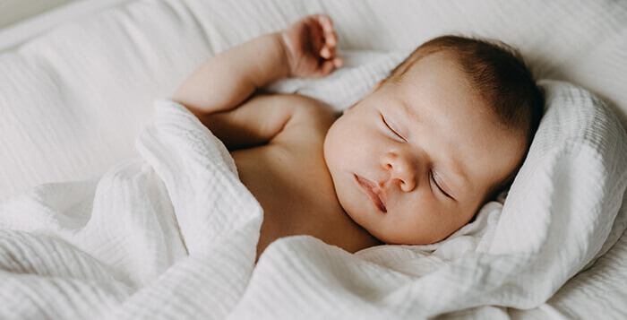 bébé dormant paisiblement enveloppé dans un lange blanc