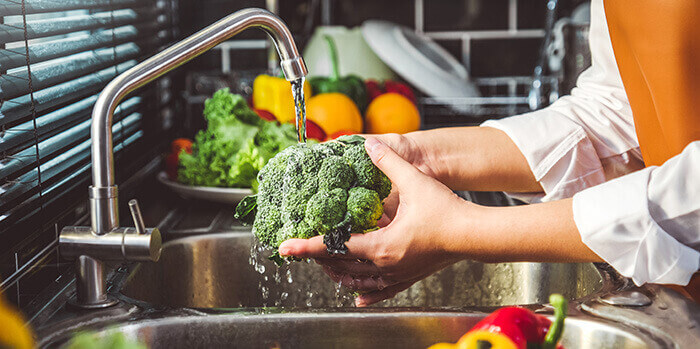 femme lavant un brocoli au robinet de cuisine