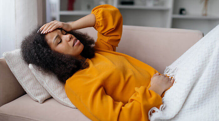 femme souffrant d'un migrain, allongée sur un canapé