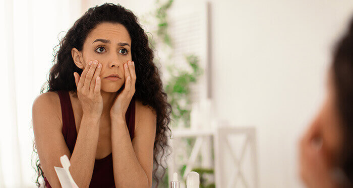 femme examinant sa peau dans un miroir