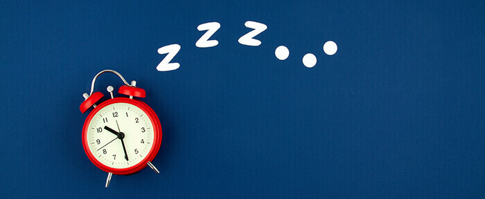 réveil sur fond bleu nuit illustrant le sommeil