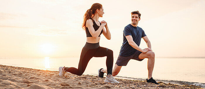 couple de sportifs s'échauffant sur la plage