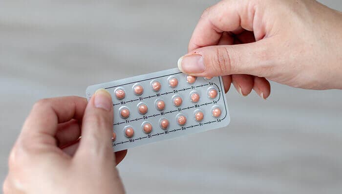 plaquette de pilule contraceptive tenue dans les mains d'une femme