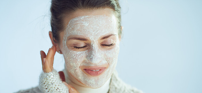 femme effectuant un gommage de la peau du visage