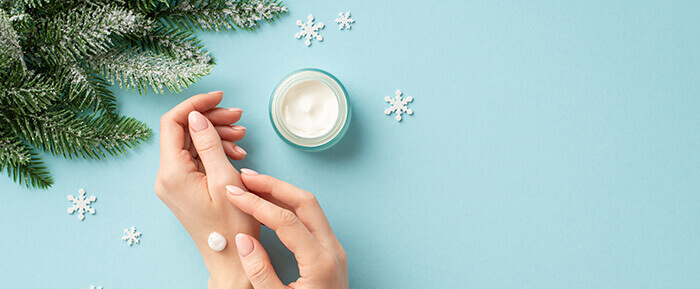pot de crème hydratante sur fond bleu avec des branches de sapin et des petits flocons