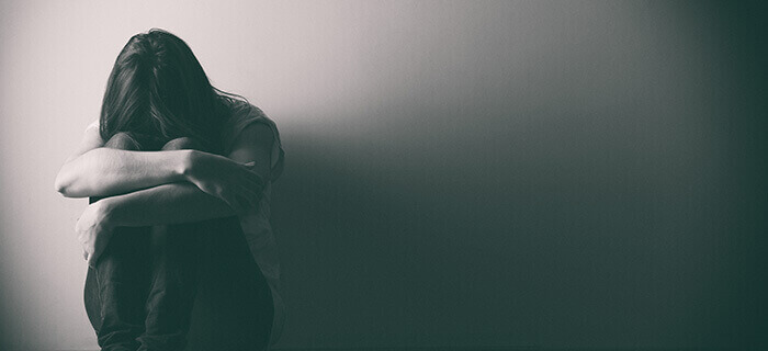 femme dépressive se tenant les genoux dans les bras