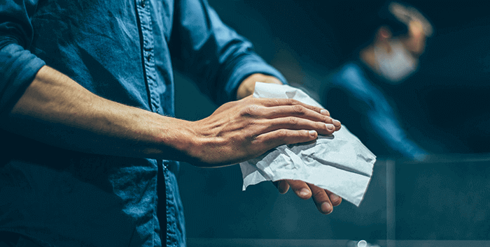 gros plan sur les mains qu'un homme se sèchent à l'aide d'une serviette en papier