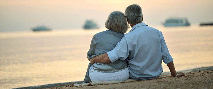 couple de personnes âgées de dos assis sur une plage