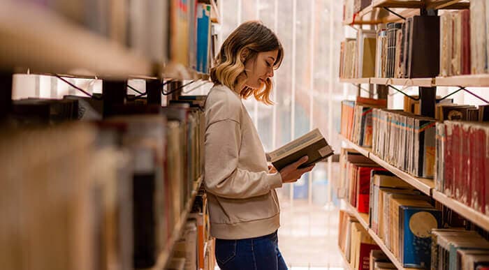 femme lisant entre deux rangées dans une bibliothèque