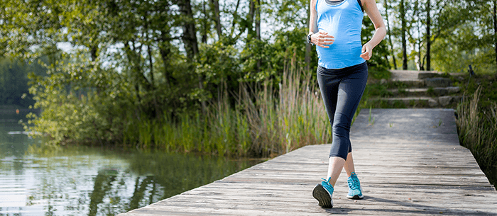 femme enceinte pratiquant la marche sur un ponton de bois