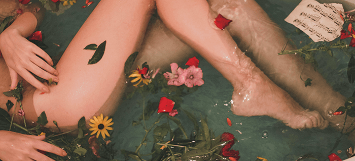 jambes de femme dans un bain avec des fleurs