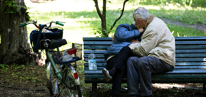 couple de personnes âgées s'embrassant sur un banc