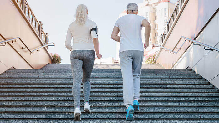 couple de séniors pratiquant la marche active dans un escalier