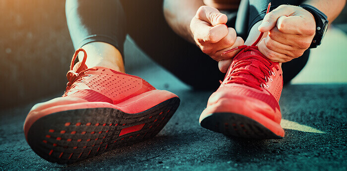 homme enfilant une paire de basket pour aller faire du sport