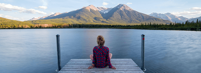 femme se relaxant sur un ponton en regardant la montagne