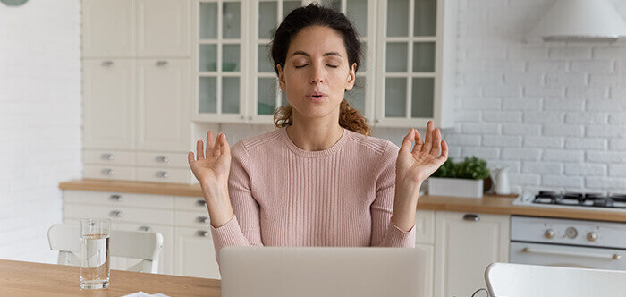 femme pratiquant un exercice de respiration devant son ordinateur