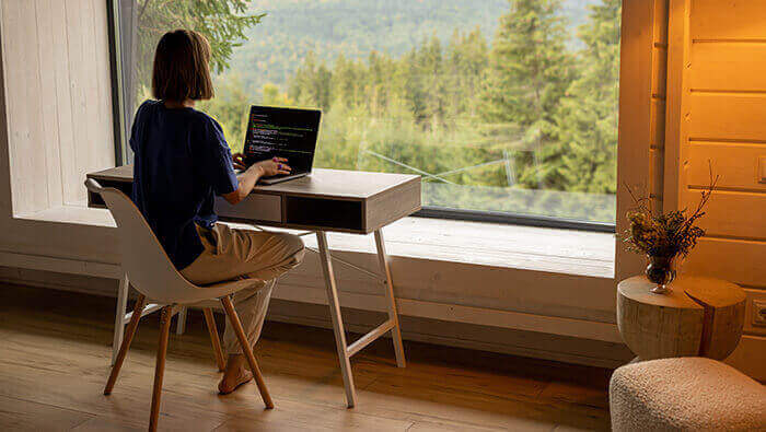 femme en télétavail dans un environnement zen face à une baie vitrée donnant sur une forêt