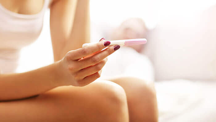 femme assise sur les toilettes consultant le résultat d'un test de grossesse