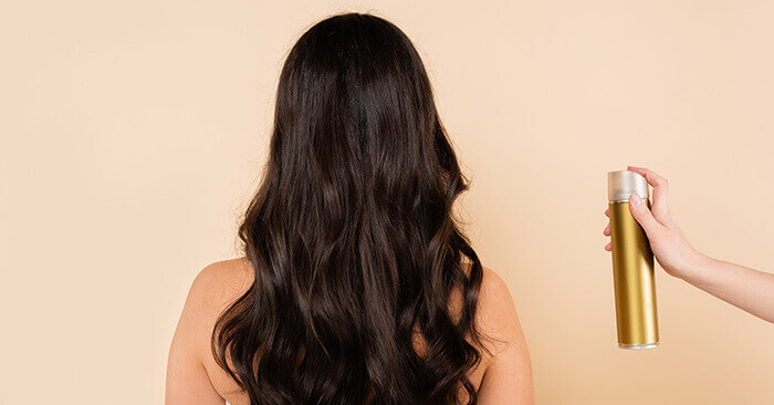 spray de laque sur longue chevelure brune