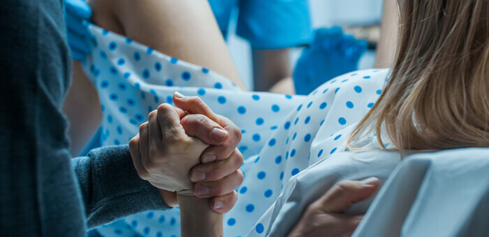 femme sur une table gynécologique en train de pousser lors de l'accouchement en serrant la main du futur papa