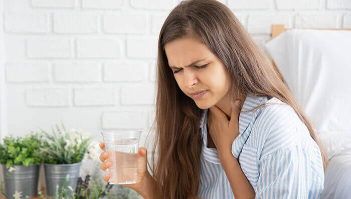 femme essayant de faire passer le hoquet en buvant un grand verre d'eau