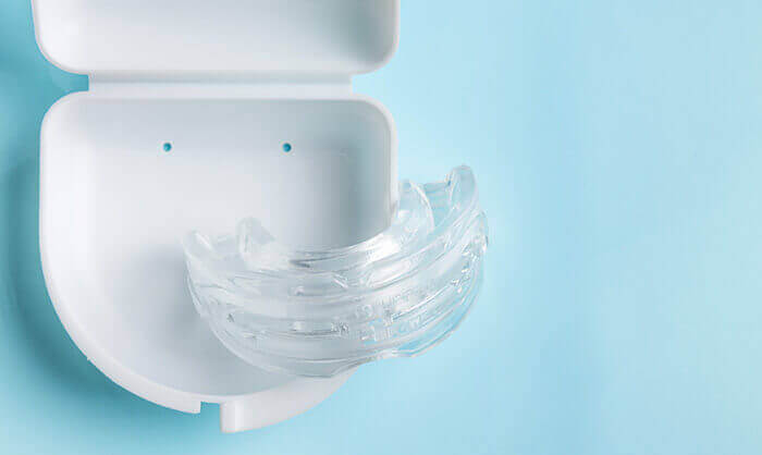 orthese mandibulaire contre le ronflement avec son boitier sur un fond bleu