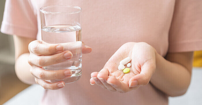 femme prenant des comprimés de médicaments génériques avec un verre d'eau