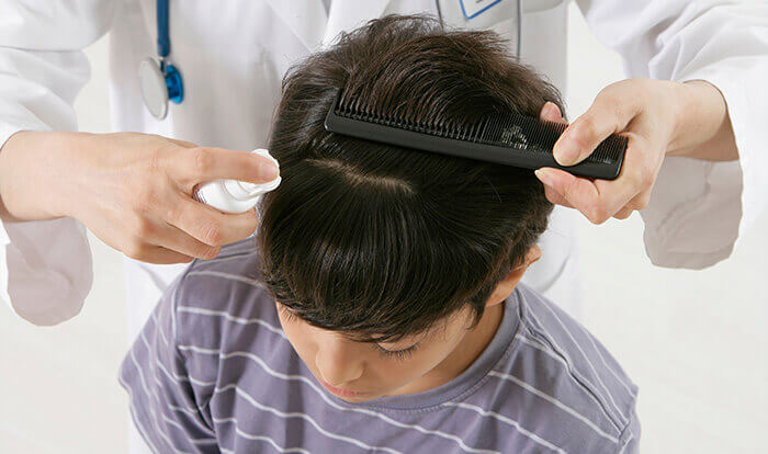 enfant qui se fait traiter les cheveux contre les poux