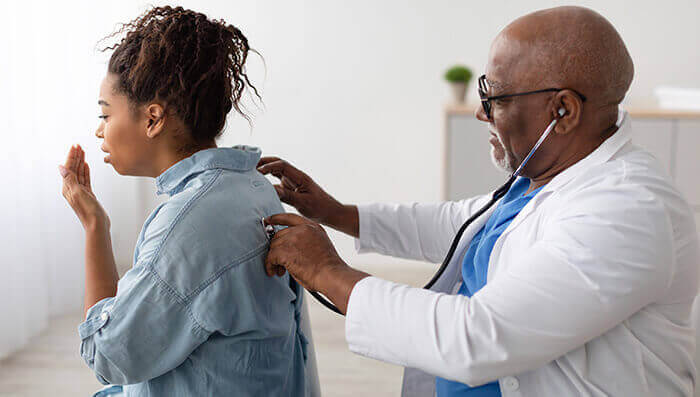 médecin qui fait tousser une patiente en consultation