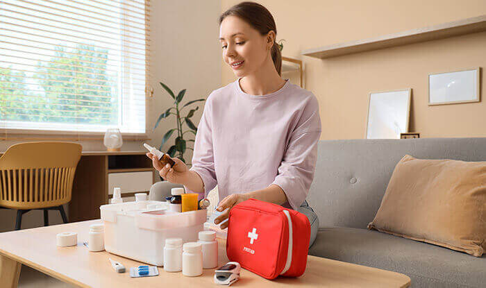 femme assise sur un canapé passant en revue les différents éléments d'une trousse de secours