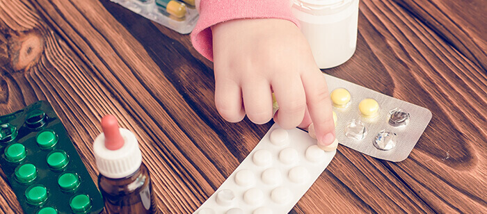 médicaments posés sur une table avec une petite main d'enfant
