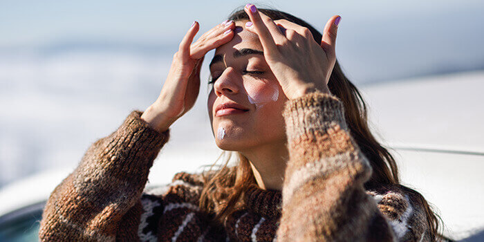 femme s'appliquant de la crème solaire à la neige