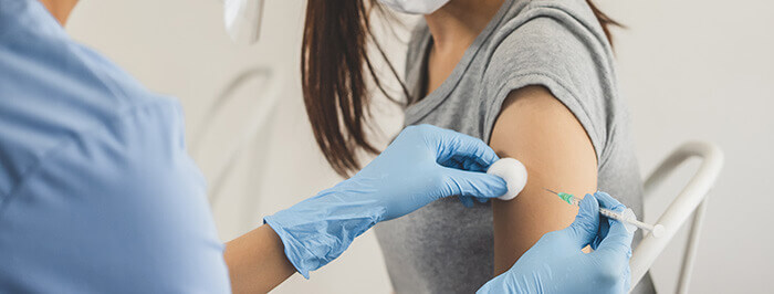 gros plan sur l'injection d'une dose de vaccin anti-grippal dans le bras d'une patiente