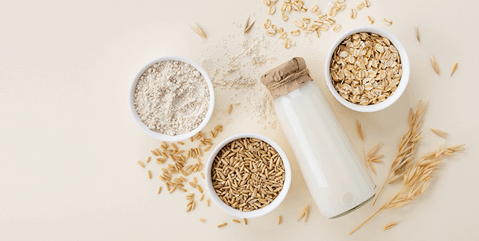 avoine sous différentes forme dans des bols, accompagnés d'une bouteille de lait