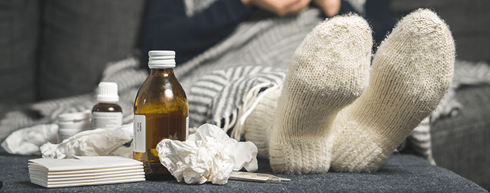 plan sur les pieds d'une personne malade avec des mouchoirs et des médicaments