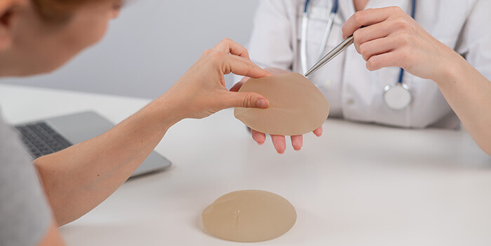 médecin présentant des prothèses mammaires en silicone à une patiente