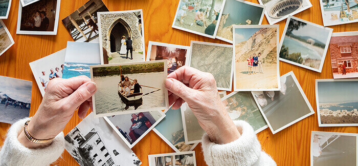 photos de jeunesse éparpillées sur uen table et consultées par une dame âgée