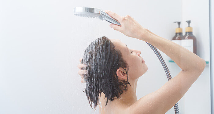 Femme rinçant son après-shampooing à l'eau claire sous la douche